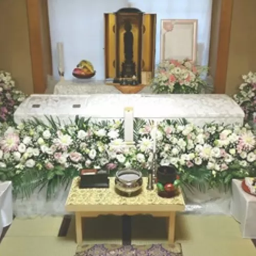 自宅葬の際の白い棺と綺麗な花束で飾られた祭壇